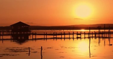 Denizde tropik gün batımı. Su ve ahşap iskelede bungalova doğru romantik bir manzara