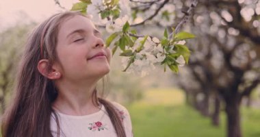 Elma bahçesindeki çiçek açan bahar ağaçlarının kokusunu alan bir kız. Bahçede folklor elbiseli Bulgar kadın