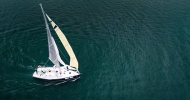 Derin mavi denizde yüzen güzel yelkenli teknesinin hava manzarası. Yarış yarışları.