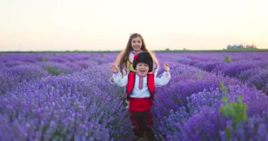 Happy children boy and girl in traditional Bulgarian folklore costumes enjoying lavender field during sunset