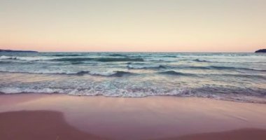 Güzel bir gün batımı ya da denizin üzerinde gün doğumu. 4K video 'da dalgalar, kum ve sakin rahatlama doğası