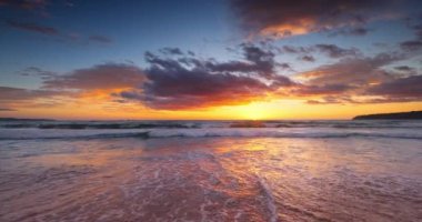 Ocean beach sunrise with color sky clouds and sun rays over sea waves, 4K video landscape