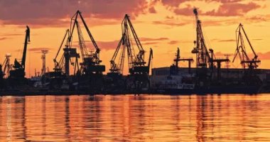 Sea commercial port and working Industrial cranes. Cargo freight ship in sea harbour at sunset. Logistic and shipping, 4K video
