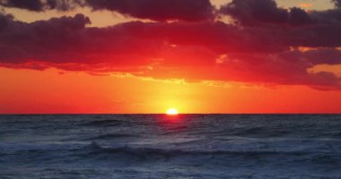 Scenic ocean beach sunrise with burning sky clouds and sea waves