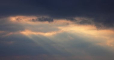 Sunbeams shining through moving dramatic white clouds. Dramatic cloudy blue sky and warm sunrise or sunset illumination, 4K video. Time lapse, peaceful, hope, religion, spiritual, nature.