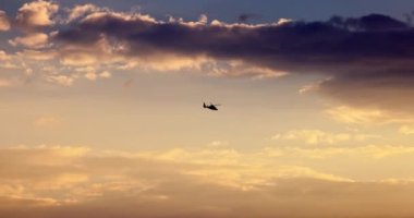 Helicopter flying in sky during scenic sunset with dramatic clouds, 4K video