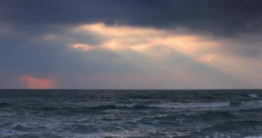 Beautiful landscape of morning sea waves and beach and sun rays between dramatic clouds