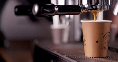 Kahve makinesi bir fincanı köpüklü sıcak siyah espresso ile dolduruyor. Barista kahve makinesiyle kahve yapıyor.. 