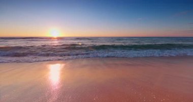 Okyanus sahili gün doğumu. Deniz kumu yıkayan okyanus dalgaları. 4k ağır çekim video.
