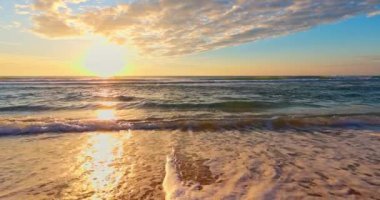 Altın okyanus sahili gündoğumu ve deniz kumu üzerindeki dalgalar, doğanın 4K görüntüsü, okyanus tropikal deniz manzarası. Düşük açı görünümü