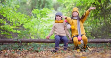 Erkek ve kız kardeş sonbahar parkında oynuyorlar. Doğadaki mutlu çocuklar. Ormana düş..