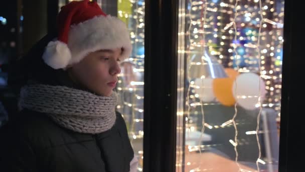 Niño en sombrero de Santas mirando en el escaparate — Vídeo de stock
