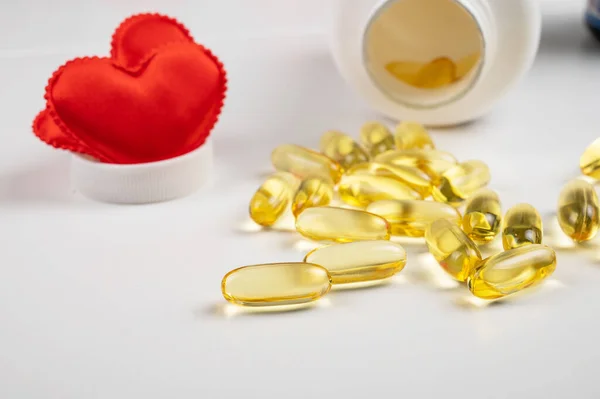 Gold fish oil isolated on white background with red hearts. — Stock Photo, Image