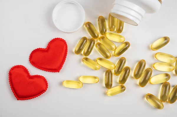Gold fish oil isolated on white background with red hearts. — Stock Photo, Image