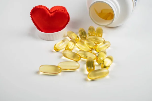 Gold fish oil isolated on white background with red hearts. — Stock Photo, Image