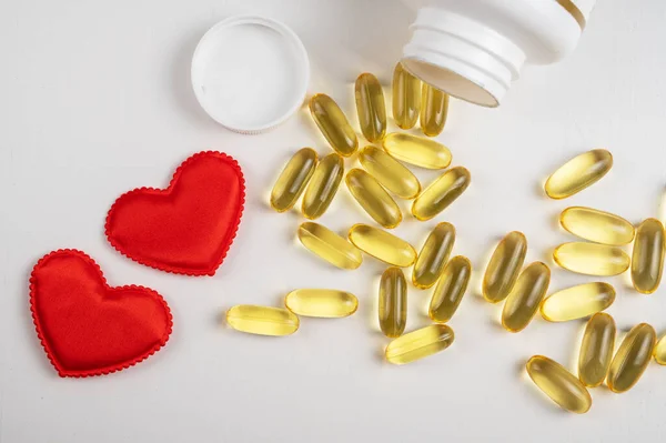 Gold fish oil isolated on white background with red hearts. — Stock Photo, Image