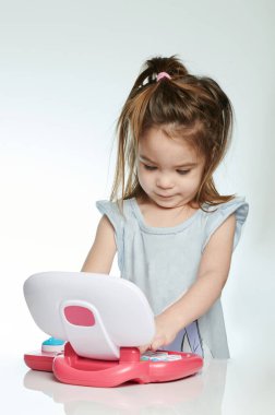 Neşeli kız öğreniyor. Beyaz stüdyo arka planında izole edilmiş laptop kullanıyor.