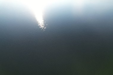 Göl su yüzeyinde dalgalanmalar ve güneş yansıması hava manzarası