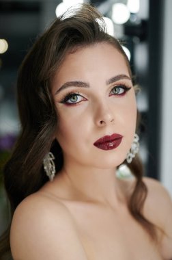 Bulanık stüdyo geçmişinde yüzü makyajlı beyaz bir kadın.