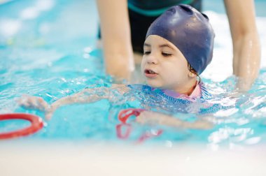 Çocuklar için okul öncesi yüzme dersleri. Çocuk yüzme havuzunda yüzüğü aldı.