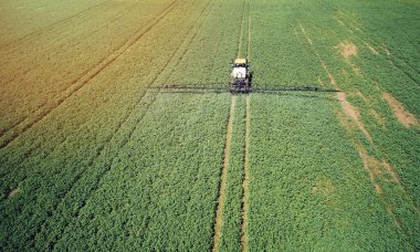 Toprak gübre tedavisi teması. Çekici makine böcek ilacı püskürtüyor. Hava aracı görüntüsü.