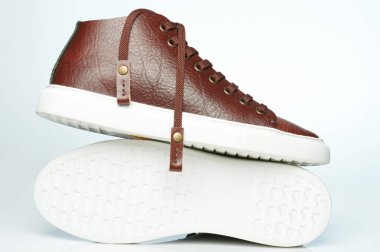 Kahverengi deri ayakkabılı, beyaz lastik tabanlı.