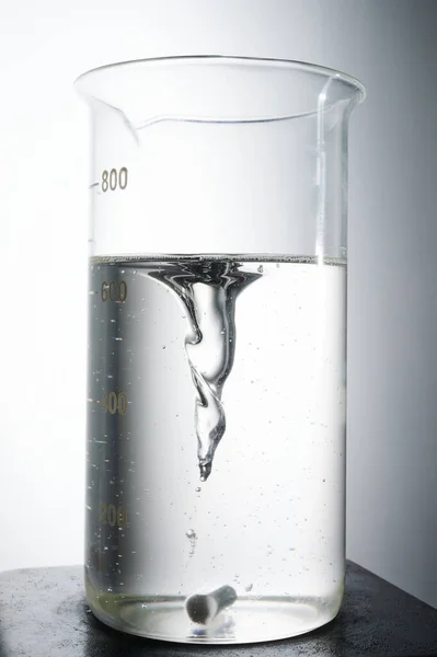 透明な液体および磁石ミキサーを用いた実験室用フラスコ — ストック写真