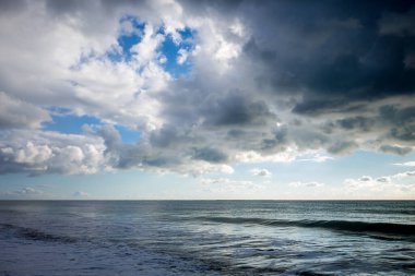 Gün batımında kumsaldan güzel bulutlu deniz manzarası