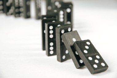 Beyaz arka planda siyah domino taşları zinciri. Domino etkisi kavramı