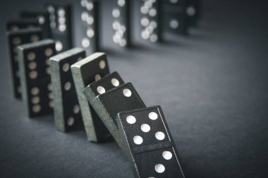 Arka planda siyah domino taşları zinciri. Domino etkisi kavramı