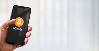 Paris - Fransa - 15 Mart 2022: Bitcoin-BTC şifreli para birimi logosu içeren iPhone akıllı telefon. Yatay Pankart