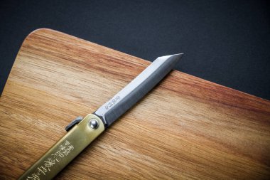 Geleneksel Japon higonokami çakısı tahta kesme tahtasının üzerinde. Siyah arkaplan