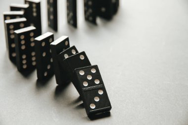 Beyaz arka planda siyah domino taşları zinciri. Domino etkisi kavramı
