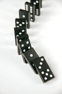 Beyaz arka planda siyah domino taşları zinciri. Domino etkisi kavramı