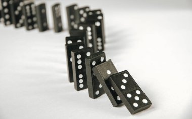 Beyaz arka planda siyah domino taşları zinciri. Domino etkisi kavramı
