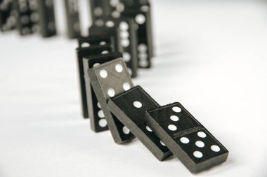 Beyaz arka planda siyah domino taşları zinciri. Domino etkisi kavramı
