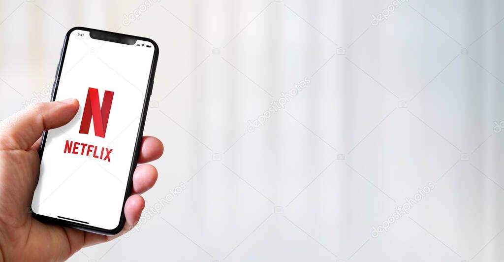 Paris - France - March 15, 2022 : Hand holding iphone smartphone with Netflix logo. Horizontal banner