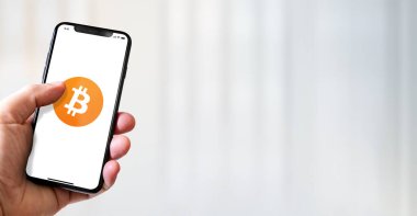 Paris - Fransa - 15 Mart 2022: Bitcoin-BTC şifreli para birimi logosu içeren iPhone akıllı telefon. Yatay Pankart