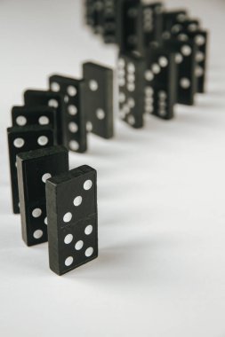 Beyaz arka planda siyah domino taşları zinciri. Domino etkisi kavramı