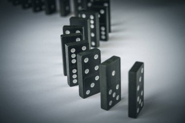 Arka planda siyah domino taşları zinciri. Domino etkisi kavramı