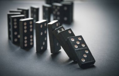 Arka planda siyah domino taşları zinciri. Domino etkisi kavramı