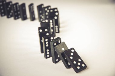 Beyaz arka planda siyah domino taşları zinciri. Domino etkisi kavramı