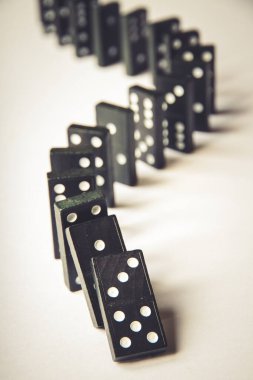 Beyaz arka planda siyah domino taşları zinciri. Domino etkisi kavramı