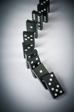 Beyaz arka planda siyah domino taşları zinciri. Domino etkisi kavramı