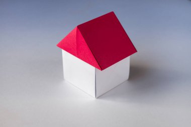 Beyaz ve kırmızı kağıt ev origamisi boş bir arkaplanda izole edildi.