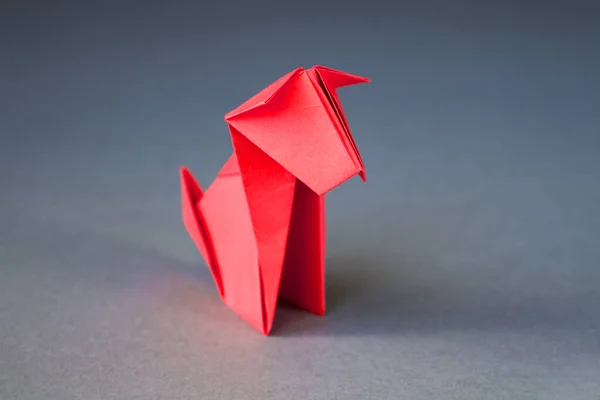 Red paper dog origami isolated on a blank grey background.