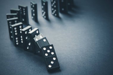 Arka planda siyah domino taşları zinciri. Domino etkisi kavramı