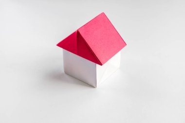 Beyaz ve kırmızı kağıt ev origamisi boş bir arkaplanda izole edildi.
