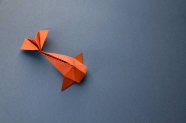 Turuncu kağıttan balık origamisi boş gri bir arkaplanda izole edilmiş.