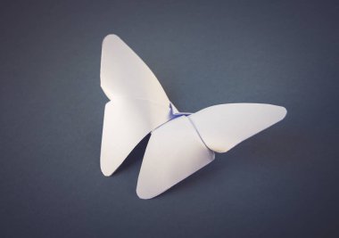 Beyaz kağıt kelebeği origamisi boş gri bir arkaplanda izole edilmiştir..